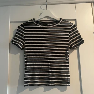 Randig ribbad topp från H&M Divided - Säljer en kortärmad ribbad topp från H&M Divided i storlek S. Toppen har svarta, vita och gråa horisontella ränder och en tight passform. Använd 1 gång 