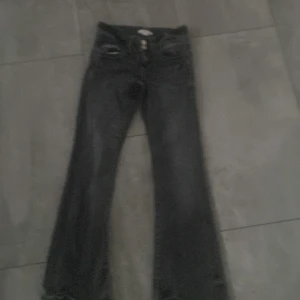 Svarta/gråa  bootcut jeans Gina Tricot - Svarta/gråa jeans från Gina Tricot i storlek 146. Säljs inte längre! Modellen har bootcut-ben och klassisk femficksdesign. Jeansen är tillverkade i ett mjukt denimtyg och har en snygg, mörk tvätt. Perfekta för dig som gillar en tidlös och trendig look. 