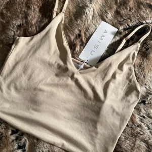 Beige linnetopp - Beige crop top med smala axelband och mjuk, slät yta. v-ringad