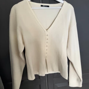 Beige kofta från Gina Tricot - Snygg beige kofta från Gina Tricot med v-ringning och dekorativa knappar framtill. Koftan har lång ärm och är tillverkad i ett mjukt material som känns skönt mot huden. Skriv gärna vid fler frågor💓💓