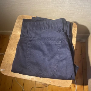 Mörkblå jeansbyxor med rak passform från Tiger of Sweden - Snygga mörkblå jeansbyxor med klassisk femficksdesign och rak passform. Perfekta för dig som gillar en enkel och stilren look. Materialet är slitstarkt jeans och färgen är djup mörkblå.