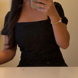 Svart kort puffärmad blus  - Säljer en svart blus med puffärmar och fyrkantig urringning. Den har en figurnära passform som framhäver siluetten. Perfekt för dig som gillar en stilren och trendig look. Den köptes i Tyskland minns ej vilken butik det va 