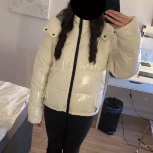 Ragwear Glansig vit pufferjacka med huva - Säljer en glansig vit pufferjacka från Ragwear med svart dragkedja och hög krage. Jackan har en mysig huva och är perfekt för kalla dagar. Den har en oversized passform och långa ärmar, vilket gör den både snygg och bekväm. Nypris: 1790kr. 💕