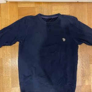 Mörkblå sweatshirt från Paul Smith - Mörkblå sweatshirt från Paul Smith Jeans med rund halsringning och broderad zebra-logga på bröstet. Klassisk passform och mjukt bomullsmaterial.👊