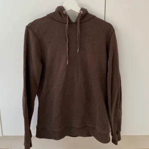 Stenströms hoodie - Säljer en brun hoodie från Stenströms i bra skick. Den är supermjuk och perfekt för höst och vinter. Hoodien har en klassisk design med dragsko i huvan och ribbade muddar vid ärmslut och nederkant. Perfekt för en chill dag eller när du vill ha något bekvämt på dig. 🧥