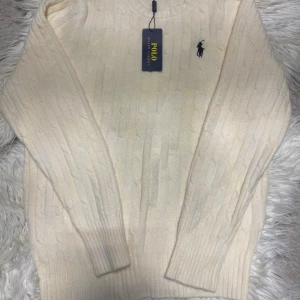 Vit stickad tröja från Polo Ralph Lauren - Säljer en krämvit stickad tröja från Polo Ralph Lauren med klassiskt kabelstickat mönster och rund hals. Tröjan har lång ärm och den ikoniska broderade loggan på bröstet. Perfekt för dig som gillar stilren och tidlös design. Leverans 🚚 Samma eller dagen efter köpet så skickar jag paketet📦Pris kan diskuteras 