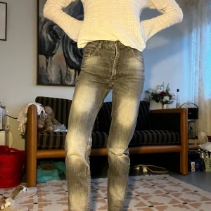 Gråa högmidjade straight jeans - Säljer ett par gråa jeans med snyggt tvättad look och raka ben. Hög midja och klassisk femficksmodell. Jeansen har en cool, lite sliten finish och är tillverkade i bomullsdenim. Perfekta för dig som gillar en avslappnad men ändå stilren vibe.