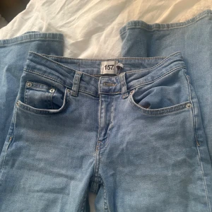 Ljusblå low waist jeans från 157 XS - Säljer ett par ljusblå jeans från 157 i storlek XS och kort längd. Modellen är low waist med klassisk femficksdesign och raka ben. Perfekta för dig som gillar en avslappnad och trendig look. Materialet är mjukt denim som sitter skönt hela dagen.