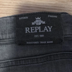 Grå jeans från Replay, storlek 14A - Säljer ett par grå jeans från Replay i klassisk femficksmodell. Jeansen har en snygg tvättad look och raka ben. Märkespatch baktill i midjan och detaljerade sömmar. Perfekta för dig som gillar stilrena och bekväma jeans.