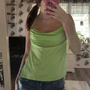 Ljusgrön halterneck linnetopp - Säljer en ljusgrön halterneck topp med snygg drapering framtill och knyt i nacken och ryggen. Toppen är ärmlös och har en croppad passform som passar perfekt till jeans eller kjol. Materialet känns mjukt och lätt, perfekt för varma dagar.