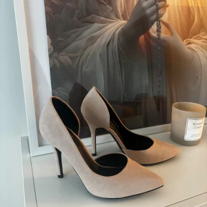 Beige pumps med spetsig tå - Snygga beige pumps med spetsig tå och hög klack från even&odd.  Skorna har en elegant och stilren design med mjukt mockamaterial som ger en lyxig känsla. Perfekta för dig som vill ha en klassisk look med en modern twist.