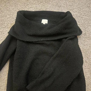 Svart off-shoulder tröja från H&M - Svart stickad från H&M i storlek S. Tröjan har en bred, nedvikt krage och långa ärmar. Storlek S, sparsamt använd.
