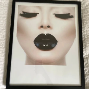 Fotoram med trä och äkta glas  - Bilderna visar en svart fotoram med äkta glas och bakstycke i träfiber. Ramen är rektangulär och har upphängningsbeslag på baksidan. Skicket ser bra ut utan synliga skador eller repor. Perfekt för att rama in foton, affischer eller konstverk. Tryck medföljer om kund vill. 