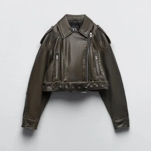 Grön croppad skinnjacka från Zara - Säljer en svart croppad skinnjacka från Zara med coola dragkedjor, bälte i midjan och klassisk krage. Jackan har långa ärmar och detaljerade sömmar som ger en edgy vibe. Perfekt för dig som vill sticka ut med en trendig look. Vill sälja så pris kan alltid diskuteras 