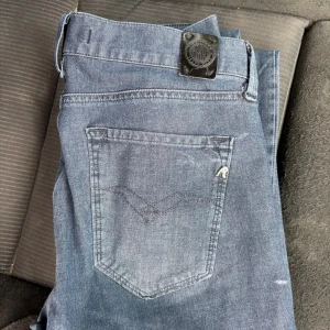 Replay jeans i blå denim, storlek 27/30 - Snygga blå jeans från Replay med klassisk femficksdesign och diskret Replay-logga vid fickan. Jeansen har raka ben och normal passform, tillverkade i mjukt denimtyg som sitter skönt hela dagen. Perfekta för dig som gillar stilrena och tidlösa jeans. Priset går att diskutera