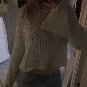 Vit stickad tröja med vida ärmar - Supersöt vit stickad tröja med vida ärmar och snyggt hålmönster. Tröjan är croppad och har en avslappnad passform, perfekt till jeans eller kjol. Materialet är mjukt och luftigt, ganska genomskinlig så linne kan bäras under, super bra skick, använd fåtal gånger då den är lite för kort o armarna tycker jag☺️