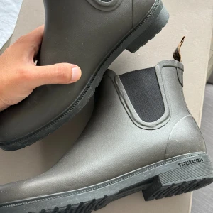 Bruna chelsea boots från Tretorn regnstövlar - Säljer ett par bruna chelsea boots från Tretorn. Skorna är i syntetmaterial med elastiska svarta paneler på sidorna och grov sula för extra grepp. Perfekta för regniga dagar och har en stilren, minimalistisk look. Liten del som behöver limmas därav priset. Nypris 1100