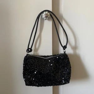 Glitter väska - En jättefin väska fullt med paljetter på! Perfekt för festival eller en rolig utgång för att klä upp outfiten! Aldrig använd. Har dragkedja och en innerficka på insidan. Säljer för 100kr