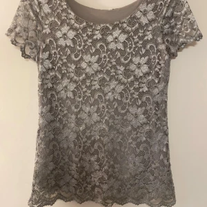 Grå/turkos spetsblus med blommönster - Säljer en grå blus i spets med vackert blommönster. Blusen har korta ärmar och rund halsringning. Knappt använd. Passar för både S och M. Skriv om du har några frågor💕