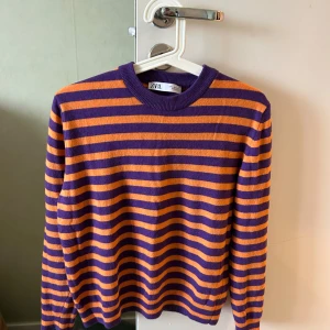 Randig lila och orange tröja från Zara - Superfin stickad tröja från Zara i lila och orange med breda ränder. Tröjan har rund halsringning och långa ärmar. Materialmix med ull, kashmir och polyamid gör den både mjuk och skön. Perfekt för dig som gillar färg och vill sticka ut lite extra.