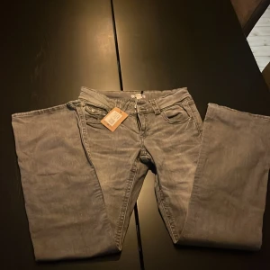 Grå jeansbyxor från Salt - Snygga grå jeansbyxor köpta från Sellpy med klassisk femficksdesign, bälteshällor och dragkedja. Jeansen har bootcut ben och dubbla knappar i midjan. Perfekta för dig som gillar en stilren och enkel look. Köpta från Sellpy men passade inte💕