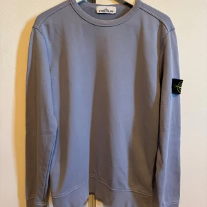 Stone Island Sweatshirt - Snygg ljusblå sweatshirt från Stone Island med klassisk patch på vänster ärm. Tröjan har rund hals och långa ärmar. Tröjan kommer passa dig som har storlek S eller M. Pris går att diskutera och svarar gärna på frågor om du har det! 