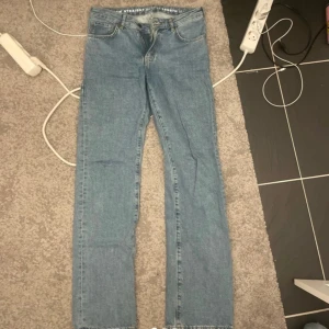Lågmidjade raka jeans i ljusblå denim - Säljer ett par lågmidjade raka jeans i ljusblå denim. Klassisk femficksmodell med dragkedja och knapp framtill. Snyggt avslappnad passform och stilren look, perfekta till sneakers eller boots.