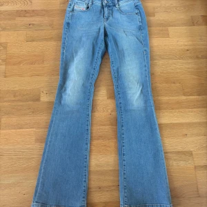Bootcut jeans från Diesel ljusblå - Säljer ett par ljusblå bootcut jeans från Diesel, modell 1969 D-EBBEY. Klassisk femficksdesign, snygga slitningar framtill och ikonisk Diesel Industry-lapp bak. Jeansen har låg midja och är tillverkade i mjuk bomullsdenim.  Köpte byxornna för 1800 kr ny pris, byxorna är nästan aldrig använda, pågrund av att jag upptäckte att byxorna va lite för små lite för sent.  Älskar dermor modellen har likadan i annan färg som sitter super bra! 