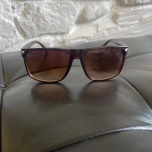 Bruna fyrkantiga solglasögon - Snygga solglasögon med bruna bågar och fyrkantig form. Glasen är tonade i brunt och bågarna har en stilren, klassisk look. Perfekta för att lyfta din stil under soliga dagar.