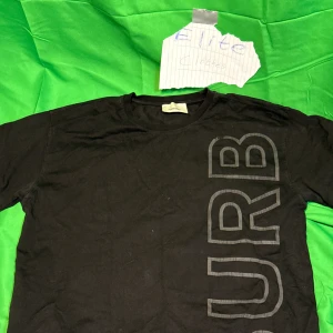 Svart Burberry t-shirt - Svart t-shirt från Burberry med stort, vertikalt tryck i grått över hela framsidan och baksidan. Klassisk rund hals och korta ärmar. Tillverkad i mjuk bomull för en skön känsla och snygg passform.Liknande modell som originalet!