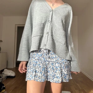 Blommig volangkjol från Zara - Supersöt kort kjol från Zara med blommigt mönster i blått, vitt och svart. Kjolen har SHORTS!! 
