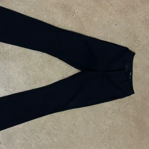 Svarta kostymbyxor från Bikbok - Snygga svarta kostymbyxor från Bikbok i klassisk rak modell. Byxorna har hällor för bälte, två fuskbakfickor och är tillverkade i ett slätt tyg som ger en stilren look. Perfekta för dig som gillar en clean och enkel stil. De är flare!