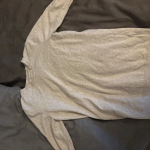 Beige stickad tröja Reserved - En stilren beige stickad tröja från Reserved med rund halsringning och korta ärmar. Tröjan har ribbade muddar vid ärmslut och nederkant, vilket ger en snygg och enkel look. Perfekt att matcha med jeans eller kjol.