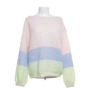 Pastellfärgad stickad tröja - Supermysig stickad tröja i pastellfärger med breda ränder i ljusrosa, ljusblå och ljusgrön. Tröjan har en loose passform och långa ärmar, perfekt för att ge en soft vibe till din outfit. Den är fluffig och har en rund halsringning.