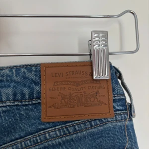 Levi's blå straight jeans low waist - Blå jeans från Levi's i modellen Low Pitch Straight. Låg midja och raka ben. Jeansen är i ett mellanblått tvättat denimtyg med snygga kontrastsömmar och Levi's ikoniska läderpatch bak i midjan.