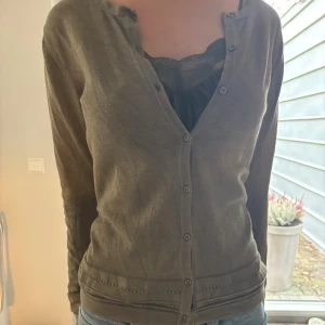 Olivgrön kofta med knappar - Snygg olivgrön kofta med v-ringning och knappar hela vägen framtill. 
