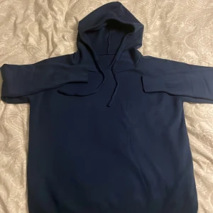 Kashmire hoodie  - Snygg mörkblå hoodie med klassisk huva och snörning framtill. Tröjan har långärmade ärmar och en enkel, stilren design utan tryck eller mönster. Perfekt för dig som gillar en clean look och vill ha något bekvämt att dra på sig.