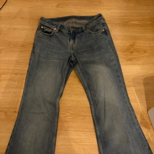 Levis 517 blå bootcut jeans - Klassiska Levis 517 jeans i blå denim med bootcut passform. Jeansen har fem fickor, dragkedja och knapp framtill samt Levis-lapp bak i midjan. Snyggt slitna detaljer och raka ben som går ut lite nertill för en tidlös look. Är i bootcut från weekday i storlek w28/34