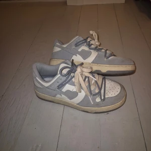 Blåvita sneakers med mockadetaljer - Snygga sneakers i blått och vitt med coola detaljer och tvåfärgade snören. Ovandelen är i mocka och syntet, med perforerad tå och klassisk låg profil. Perfekta för dig som gillar streetstyle och vill ha något som sticker ut. Köpt för ca 3 år sedan och inte använts på länge💓
