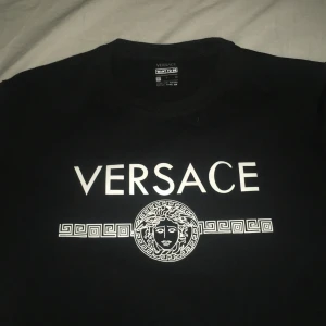 Svart  fin sweatshirt med tryck - Svart sweatshirt med stort vitt logotryck och Medusa-motiv på bröstet. Rund halsringning och klassisk passform. Materialet känns som mjuk bomull, perfekt för dig som vill ha en clean och stilren look med designer-vibe. Passar mer som S eller M, mindre i storlek 