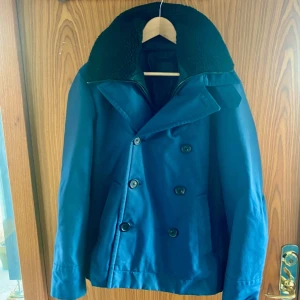 Blå skepparkavaj från Prada - Säljer en stilren blå skepparkavaj från Prada i storlek 52. Passar som en M enligt mig. Pälsen är avtagbar. 