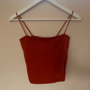 Röd linnetopp från Gina Tricot - Säljer en röd linnetopp från Gina Tricot i storlek S. Toppen har smala axelband och är croppad med en enkel, rak form. Materialet är mjukt och lätt bomull, 