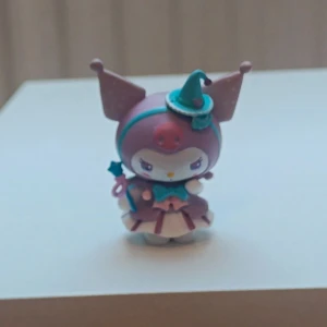 Kurumi hello Kitty Sanrio samladfigur - Söt Kuromi-figur från Sanrio, klädd som häxa med hatt och trollstav. Pastellfärger och fina detaljer, perfekt för samlare eller som dekoration. Figuren ser ut att vara i mycket gott skick utan synligt slitage eller defekter.