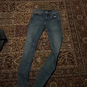Blå skinny jeans från Tiger of Sweden - Säljer ett par blå  jeans från Tiger of Sweden. Jeansen har klassisk femficksdesign, smal passform och läderpatch med logga bak i midjan. Perfekta för dig som gillar en bra och stilren look. Materialet är mjukt och stretchigt jeans.