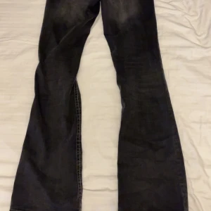 Svarta bootcut jeans Gina Tricot 158 - Snygga svarta jeans från Gina Tricot i storlek 158. Jeansen har bootcut-modell med utsvängda ben och markerade sömmar. Klassisk femficksdesign och dubbla silverknappar framtill. Perfekta för dig som gillar en cool och tidlös look.