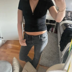 Svart v-ringad topp från BikBok - Svart, tight topp från BikBok med djup v-ringning och korta ärmar. Sitter figurnära och har en lätt croppad passform. 