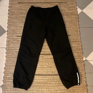 Mckinley täck byxor - Mckinley täck byxor i svart med reflex på botten och knappar. Reglerings band i midjan.