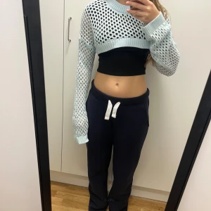 Ljusblå croppad stickad tröja Monki - Säljer en ljusblå croppad stickad tröja från Monki i storlek XS. Tröjan har ett coolt hålmönster, ribbad kant vid hals och nederdel samt långa ärmar. Perfekt att styla över ett linne eller t-shirt för en trendig look.