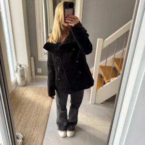 Svart kappa - Säljer en svart kappa och bred krage. Jackan har en stilren, klassisk look med långärmade ärmar. Perfekt för dig som gillar en lite mer edgy och tidlös stil.