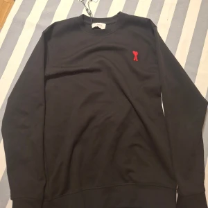 Svart sweatshirt från Ami med rött hjärta - Svart sweatshirt från AMI Paris som är helt ny, var för liten därför säljer jag den. Finns kvar och priset är inte helt fast i sten, tar bytten!!
